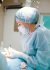 pexels-photo-4586993-4586993 Female medical professional in surgical attire operating in a sterile room, focusing on patient care.